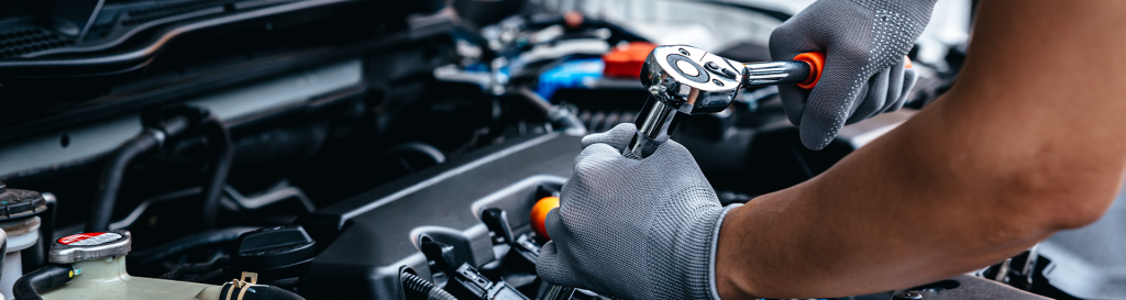 A zoomed in photo of a technician working on a car engine. Schedule your service at Mazda of Spartanburg.